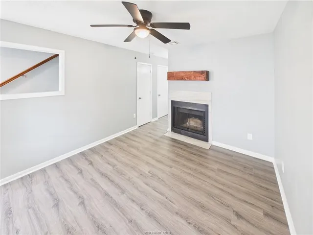 a view of an empty room with wooden floor fireplace and a window