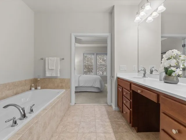 a spacious bathroom with a tub sink and mirror