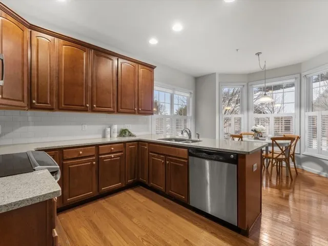 a kitchen with stainless steel appliances granite countertop wooden cabinets a sink dishwasher a stove and a refrigerator with wooden floor