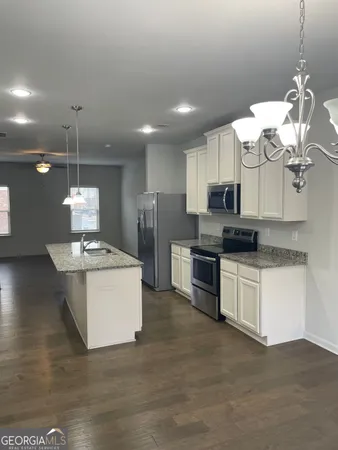 a kitchen with stainless steel appliances granite countertop a sink a stove a refrigerator and white cabinets