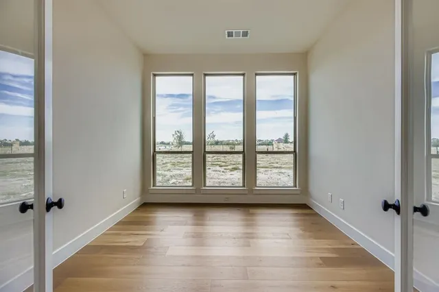 a view of empty room with wooden floor and fan