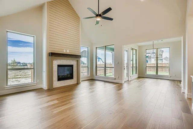 an empty room with wooden floor fireplace and windows