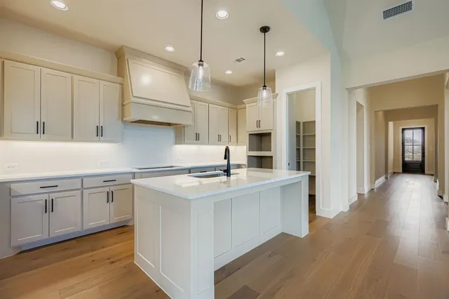 a kitchen with a sink wooden floor and white cabinets