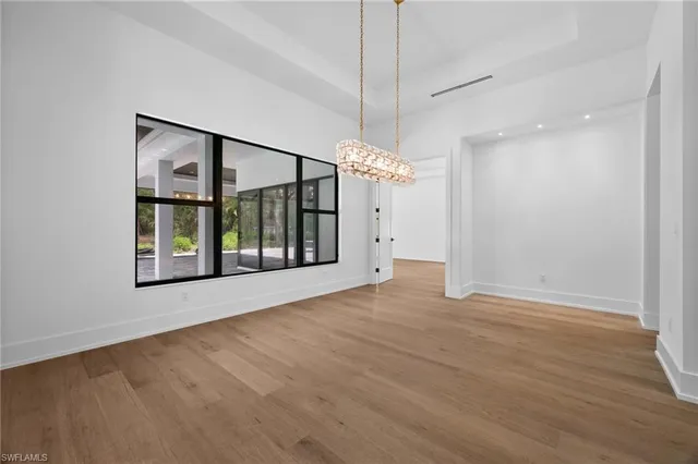 a dining room with furniture a chandelier and wooden floor