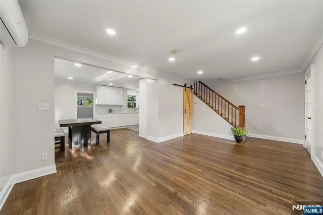 a view of an empty room with wooden floor and chairs