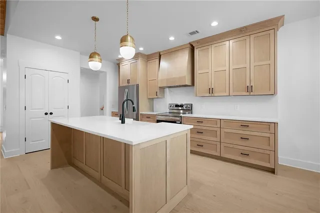 a kitchen with cabinets stainless steel appliances a sink and wooden floor
