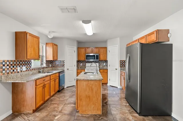 a kitchen with stainless steel appliances granite countertop a refrigerator a stove and a sink