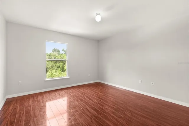 an empty room with wooden floor and window