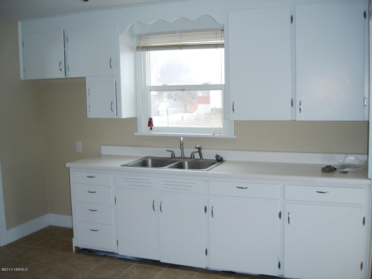 10608 Hughes Road Yakima, WA 98903 - Photo 5 of 10 a kitchen with white cabinets appliances a sink and a window