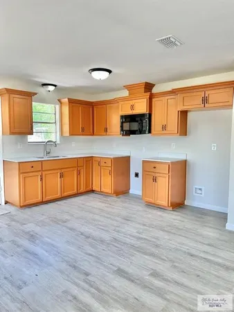 a view of kitchen with stainless steel appliances wooden floor and a sink