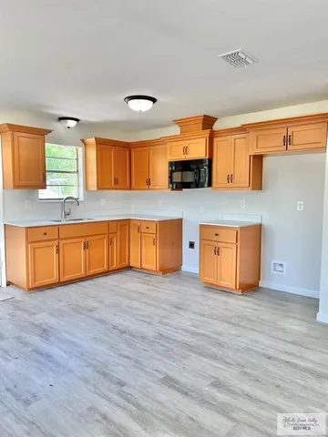 a view of kitchen with stainless steel appliances wooden floor and a sink