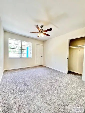 an empty room with windows and ceiling fan