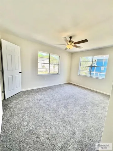 an empty room with windows and ceiling fan