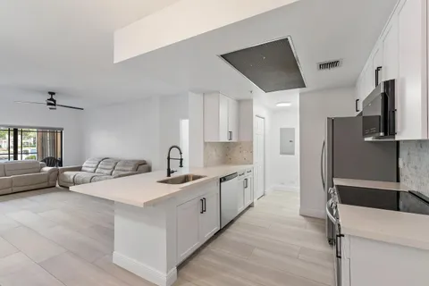 a large white kitchen with stainless steel appliances a sink and cabinets