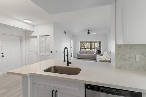 a kitchen with a sink dishwasher and white cabinets