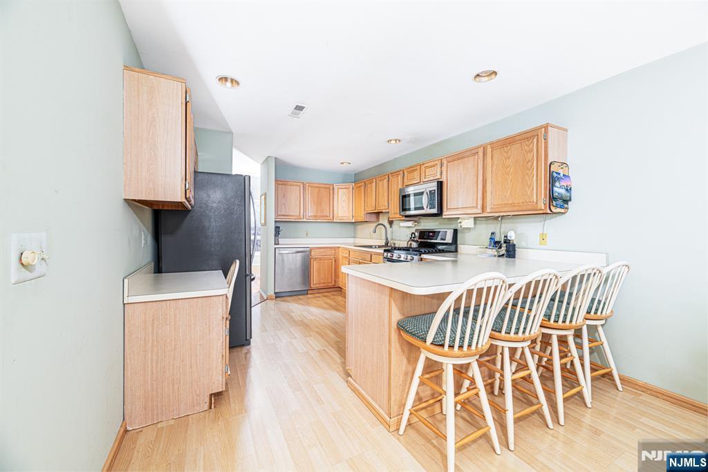 44 Mill Pond Road Little Falls, NJ 07424 - Photo 20 of 37 a kitchen with stainless steel appliances kitchen island granite countertop a stove a refrigerator a microwave oven with white cabinets and wooden floor