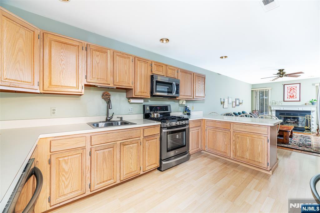 44 Mill Pond Road Little Falls, NJ 07424 - Photo 21 of 37 a kitchen with stainless steel appliances granite countertop a stove top oven a sink dishwasher and a microwave oven with white cabinets