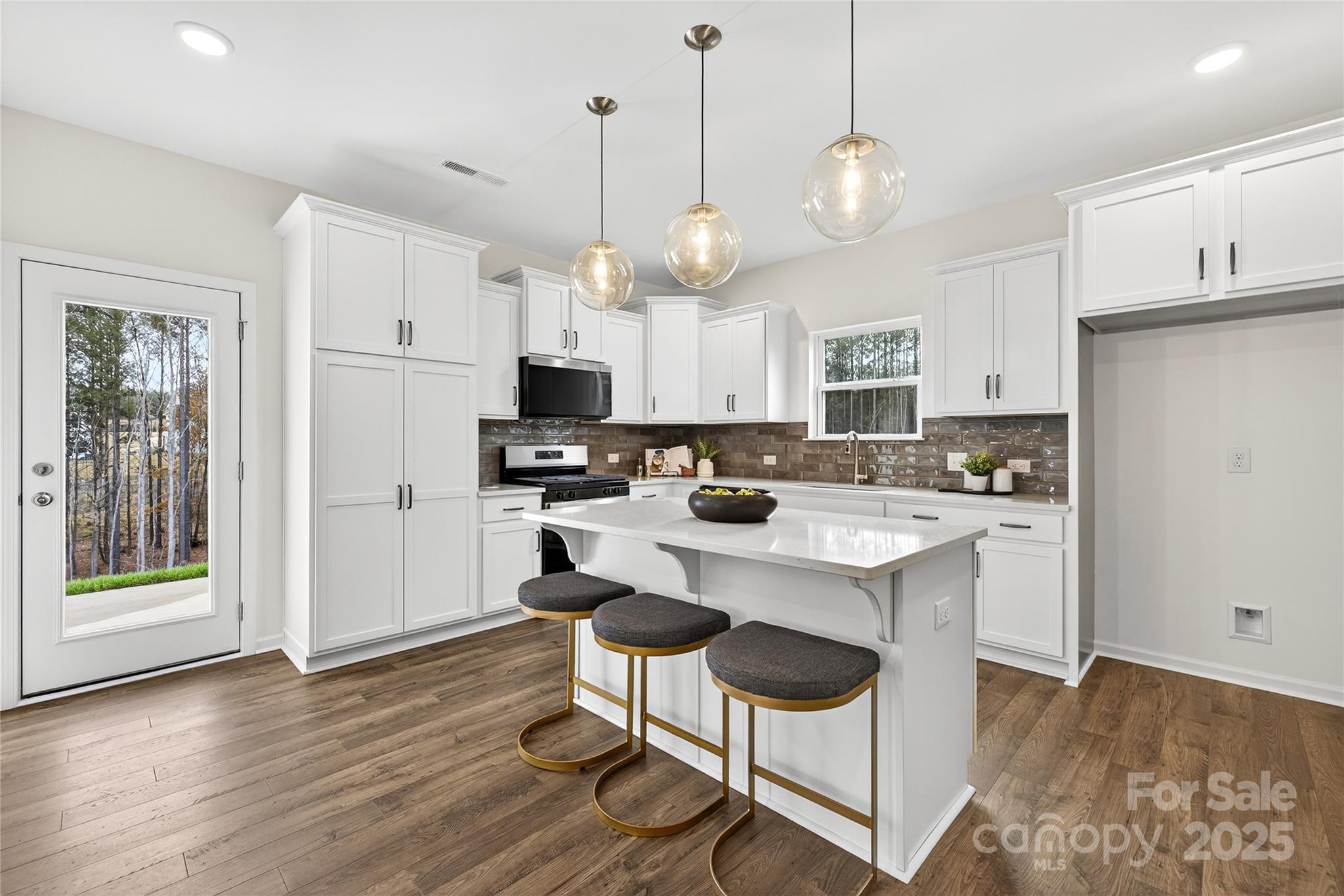 10423 Lakeshore Drive, Unit 71 Lancaster, SC 29720 - Photo 4 of 31 a kitchen with stainless steel appliances kitchen island granite countertop a refrigerator a stove a microwave oven a dining table and chairs with wooden floor
