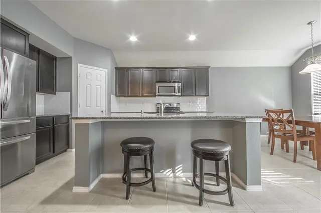 a kitchen with stainless steel appliances granite countertop a table chairs microwave and sink