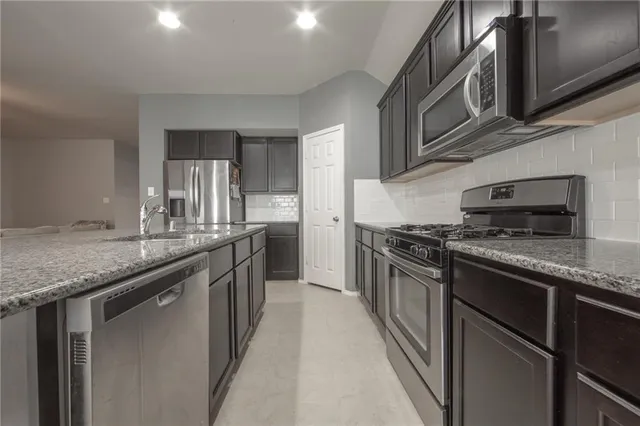 a kitchen with stainless steel appliances granite countertop a sink and stove top oven