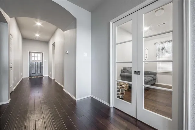 a view of a hallway with wooden floor closet and front door