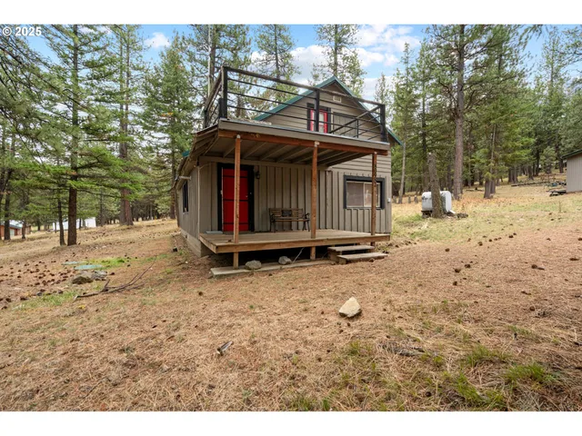 a view of a wooden house with a yard covered in snow