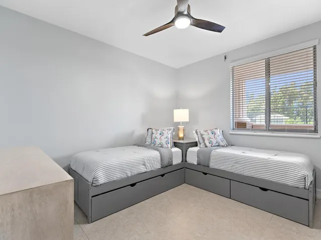 a bedroom with two beds and ceiling fan