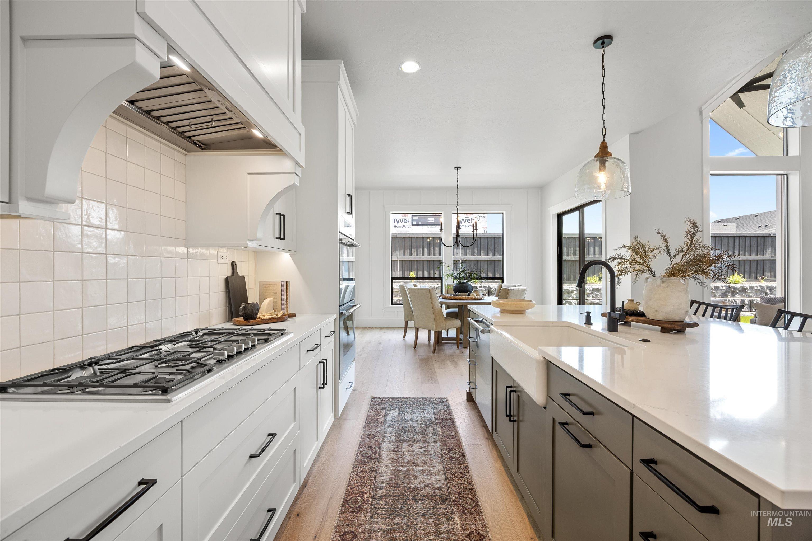 5940 South Pinpoint Way Meridian, ID 83642 - Photo 23 of 40 Gourmet kitchen featuring a gas range, white subway tile backsplash, white shaker cabinetry, and a large island with a farmhouse sink