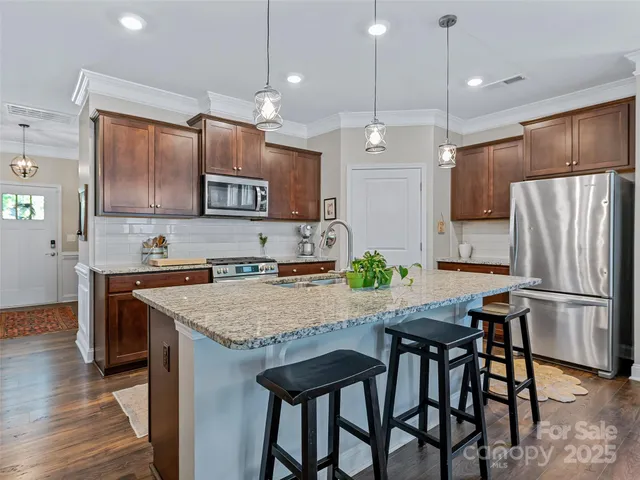 a kitchen with granite countertop a table chairs stainless steel appliances and wooden floor