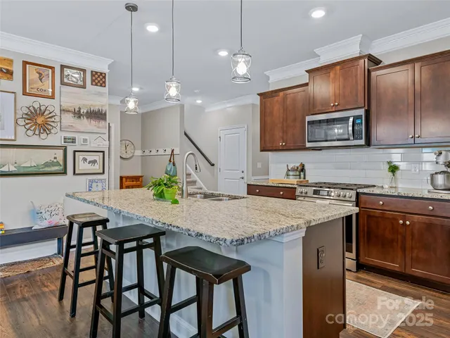 a kitchen with stainless steel appliances granite countertop a kitchen island a stove a table and chairs in it
