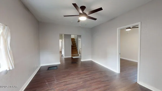 an empty room with wooden floor and a ceiling fan