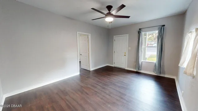 an empty room with wooden floor and windows