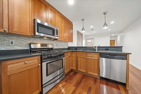 a kitchen with stainless steel appliances granite countertop a sink a stove top oven a counter space and cabinets