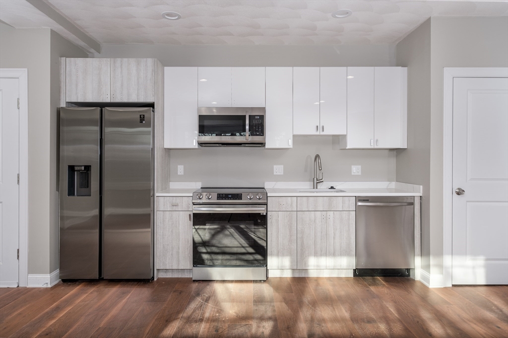 119-121 Addison Street, Unit 3 Boston, MA 02128 - Photo 2 of 13 a kitchen with a refrigerator stove and white cabinets