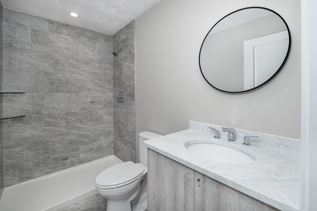 119-121 Addison Street, Unit 3 Boston, MA 02128 - Photo 6 of 13 a bathroom with a granite countertop sink toilet and a mirror