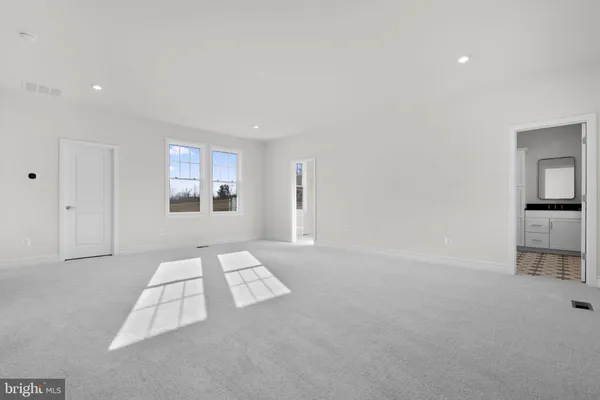 an empty room with windows and way to kitchen