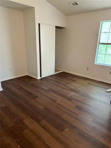 an empty room with wooden floor and windows