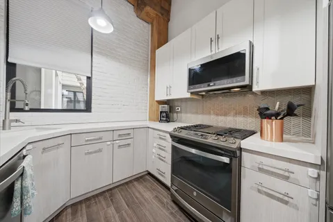 a kitchen with cabinets stainless steel appliances and wooden floor