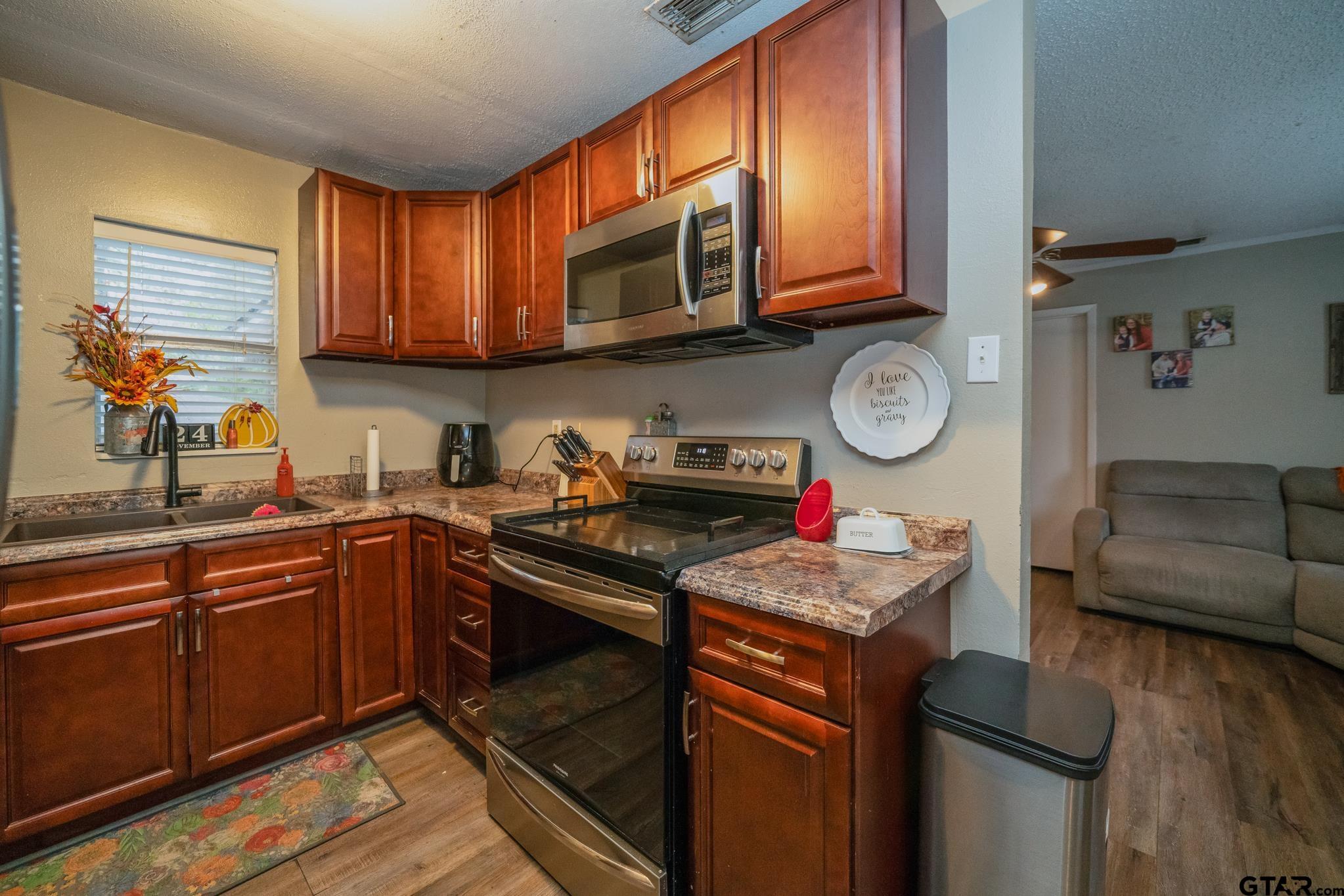 208 East Center Street White Oak, TX 75693 - Photo 13 of 31 a kitchen with stainless steel appliances granite countertop a stove top oven a sink dishwasher and cabinets with wooden floor