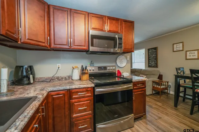 a kitchen with stainless steel appliances granite countertop a stove top oven a sink dishwasher and cabinets with wooden floor
