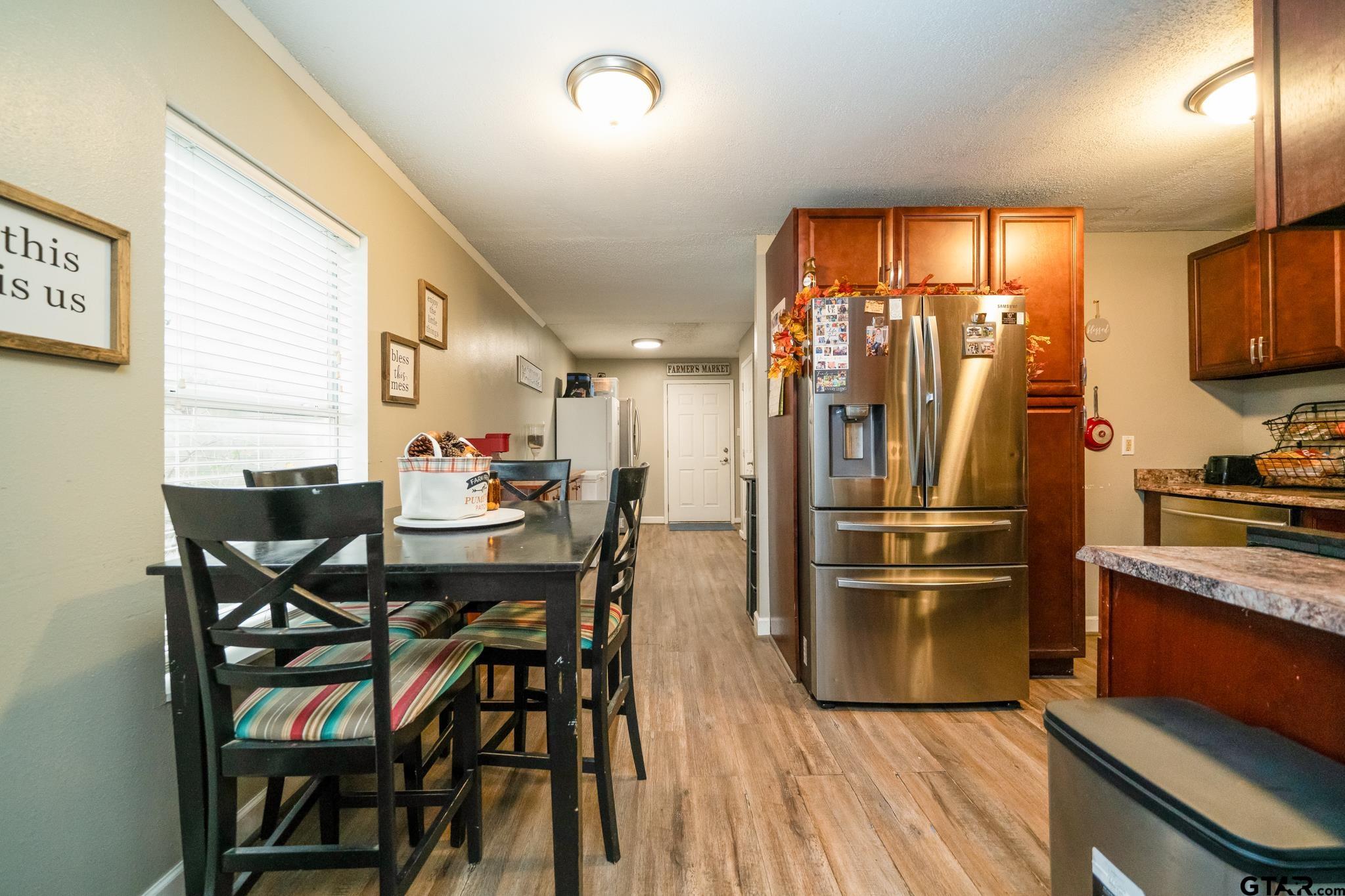 208 East Center Street White Oak, TX 75693 - Photo 17 of 31 a kitchen with stainless steel appliances a dining table chairs refrigerator and sink