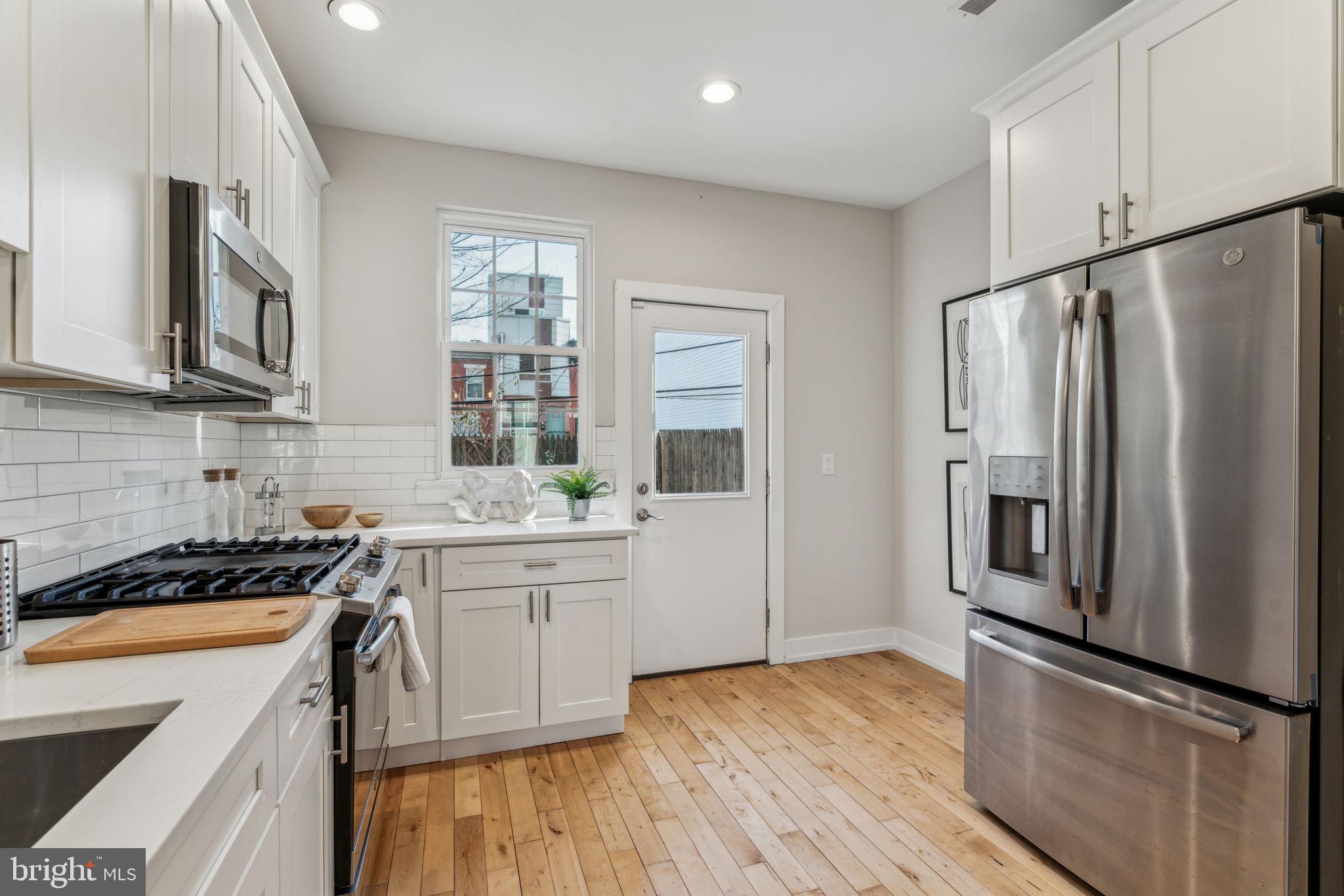 1335 North 30th Street Philadelphia, PA 19121 - Photo 14 of 58 a kitchen with stainless steel appliances granite countertop a refrigerator a sink dishwasher a stove and white cabinets with wooden floor