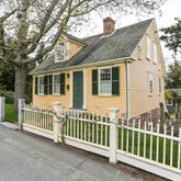 a view of a house with a small yard and large trees
