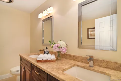 a bathroom with a granite countertop sink a large mirror and a toilet