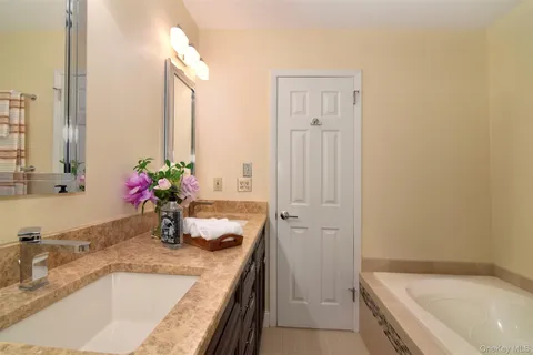 a bathroom with a granite countertop sink and a bathtub