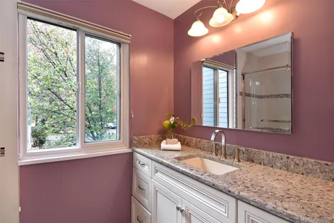 a bathroom with a granite countertop sink and a large mirror