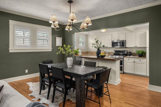 a dining room filled chandelier and kitchen view