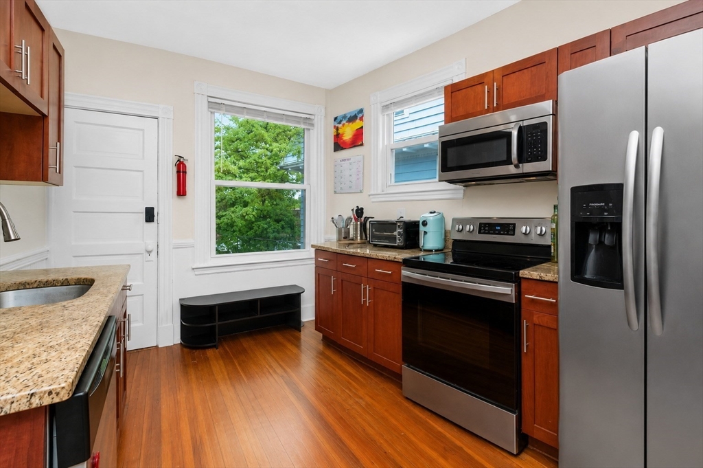 8 Colliston Road Boston, MA 02135 - Photo 4 of 40 a kitchen with stainless steel appliances granite countertop a stove a microwave and a hard wood floors