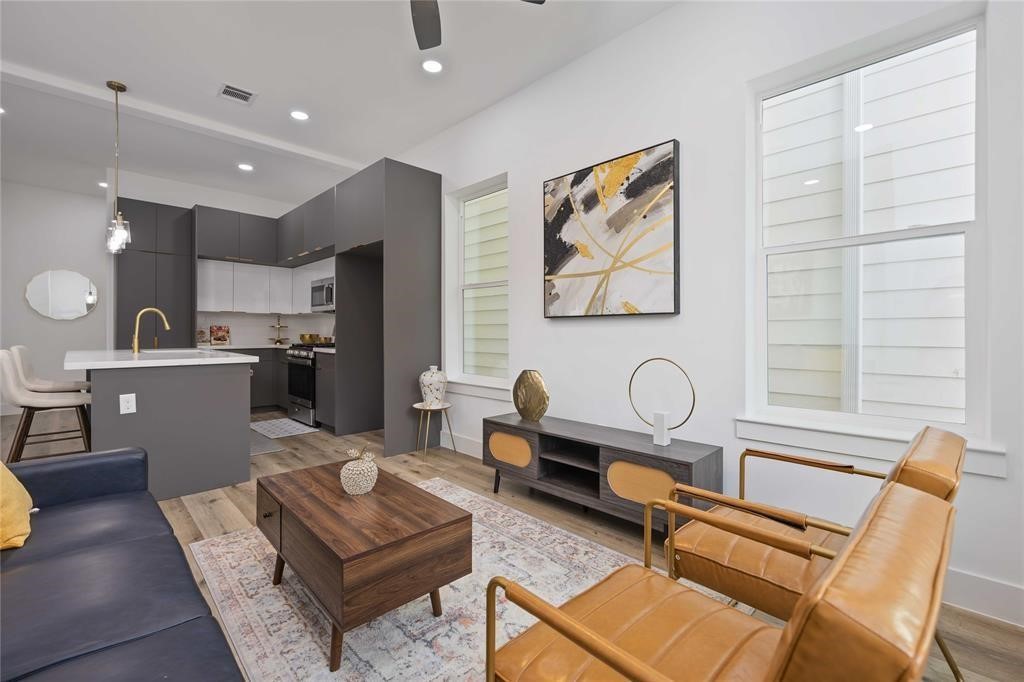 a living room with furniture a dining table and kitchen view with wooden floor