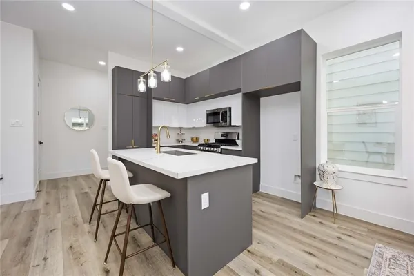 a kitchen with stainless steel appliances kitchen island granite countertop a refrigerator a stove a sink dishwasher with a dining table and chair with wooden floor